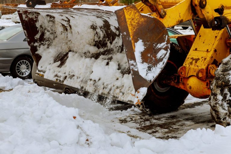 Close-up of tractor snow plow clears streets of snow after blizzard.